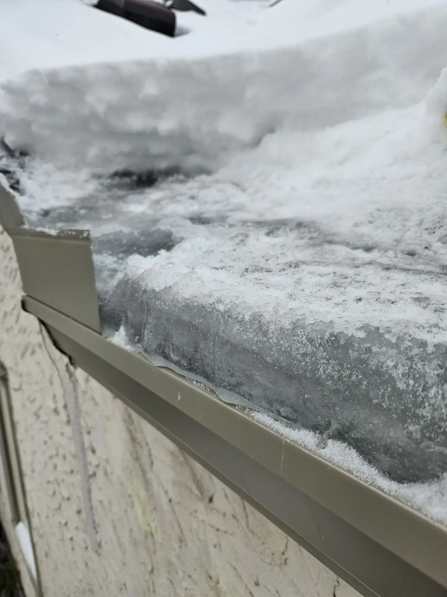 Ice and snow built up along a gutter edge on a Twin Cities home
