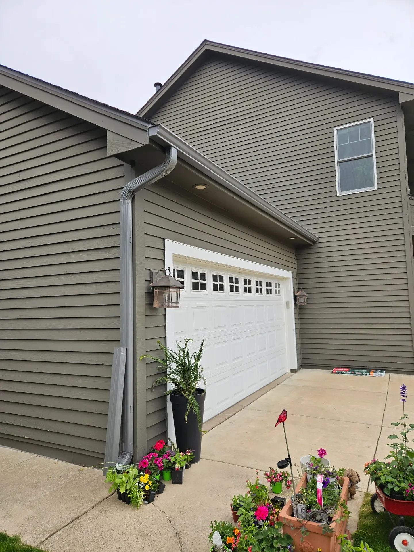 Newly installed bronze downspout running down a stucco home